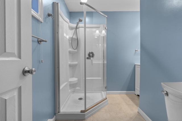 bathroom with a stall shower, baseboards, toilet, and tile patterned floors