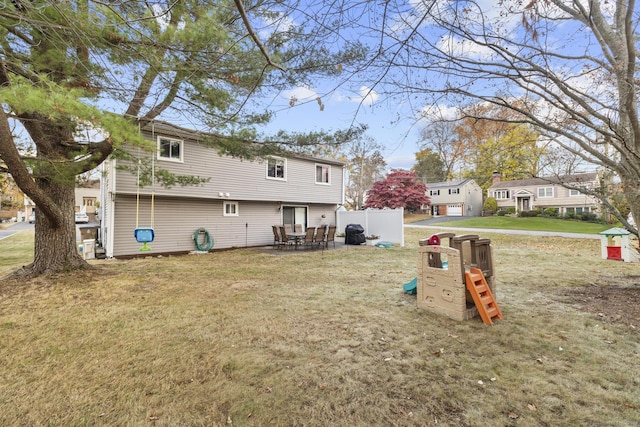 rear view of house featuring a playground and a lawn