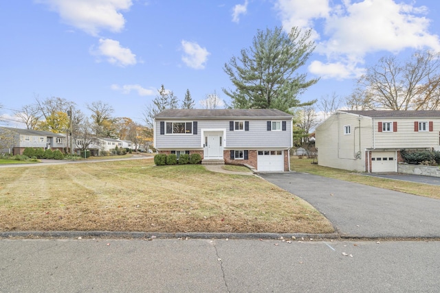 bi-level home with driveway, a garage, a front lawn, and brick siding