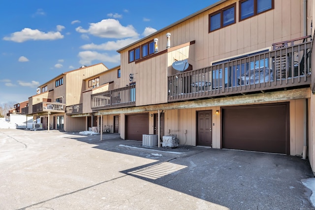 view of building exterior with driveway, an attached garage, and cooling unit