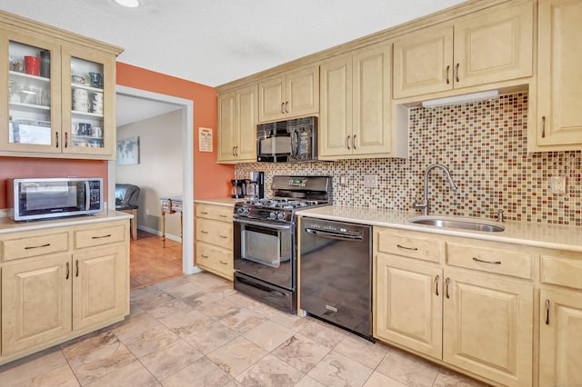 kitchen with light countertops, backsplash, glass insert cabinets, a sink, and black appliances