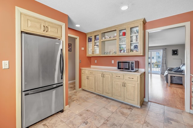 kitchen with baseboards, glass insert cabinets, stainless steel appliances, a textured ceiling, and light countertops