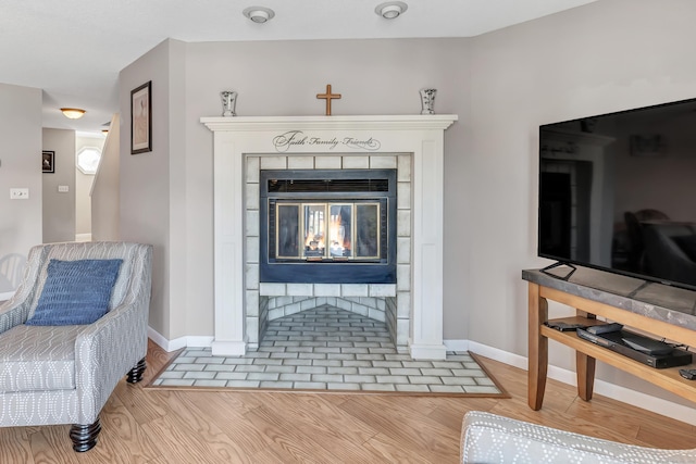 interior details with a tiled fireplace, wood finished floors, and baseboards