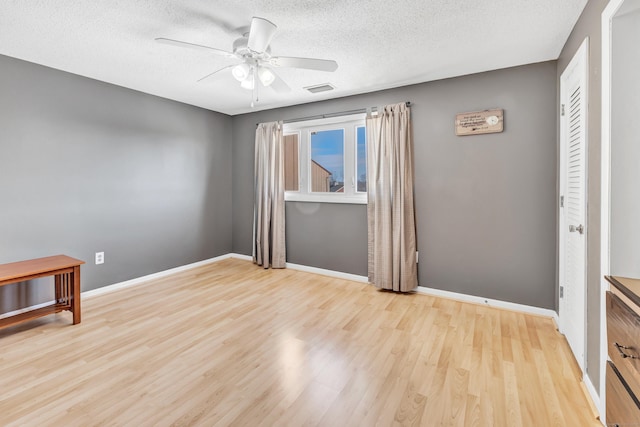 empty room with a ceiling fan, light wood-type flooring, and baseboards