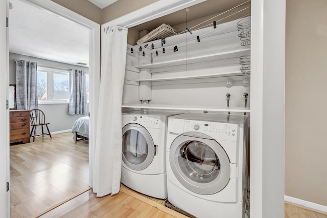 laundry room featuring washer and dryer, laundry area, baseboards, and light wood finished floors