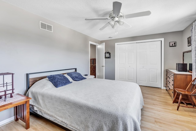 bedroom featuring a textured ceiling, visible vents, a ceiling fan, a closet, and light wood-type flooring