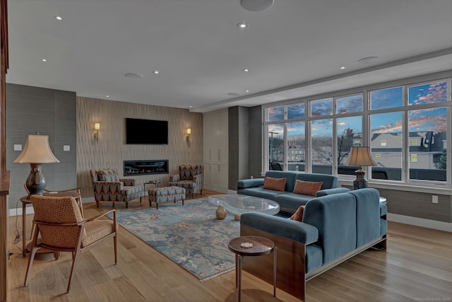 living room with a glass covered fireplace, wood finished floors, and recessed lighting