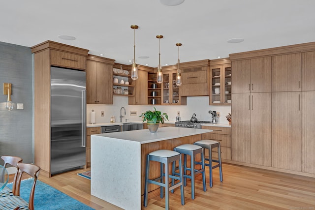 kitchen with a kitchen breakfast bar, appliances with stainless steel finishes, light wood-type flooring, a center island, and open shelves