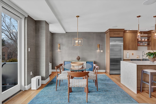 dining space with light wood-style floors, baseboards, and a notable chandelier