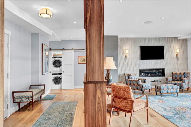 living room with light wood finished floors, a barn door, stacked washer / dryer, a glass covered fireplace, and baseboards