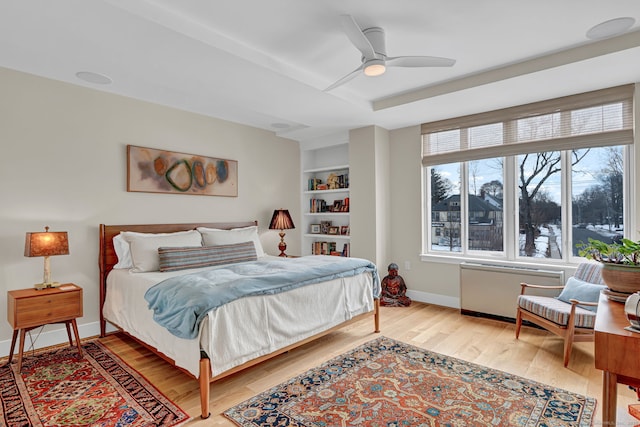 bedroom with light wood-style flooring, baseboards, and a ceiling fan