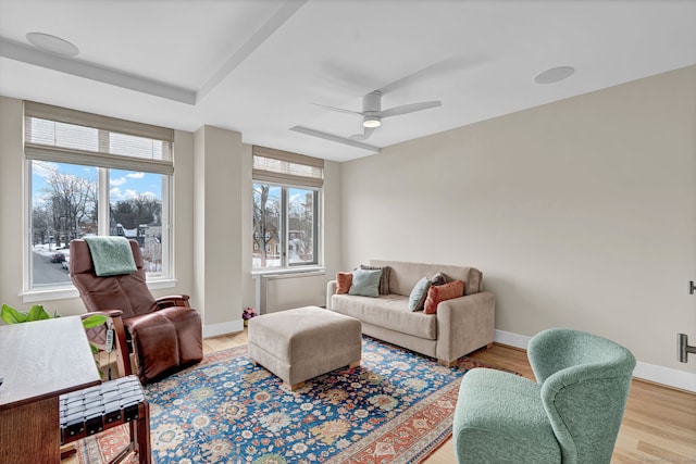 living room with light wood-type flooring, ceiling fan, and baseboards