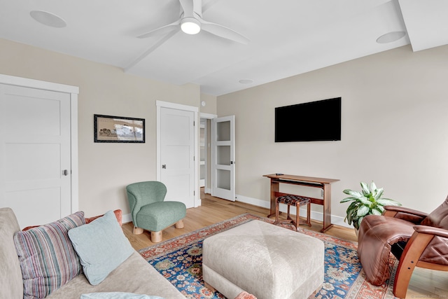 living area featuring baseboards, a ceiling fan, and wood finished floors