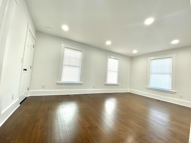 spare room featuring dark wood-type flooring, recessed lighting, baseboards, and visible vents