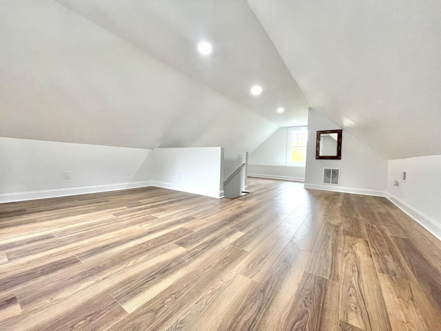 additional living space featuring visible vents, dark wood finished floors, baseboards, lofted ceiling, and recessed lighting