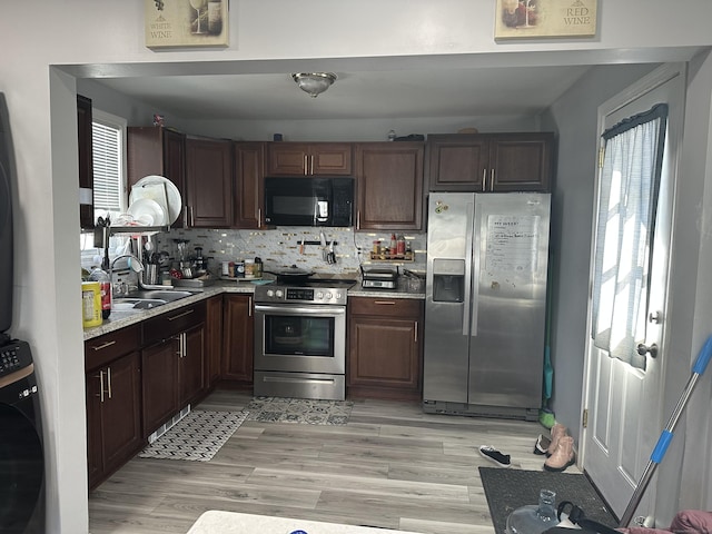 kitchen with washer / dryer, light wood-style flooring, backsplash, stainless steel appliances, and a sink