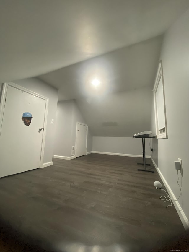 additional living space with lofted ceiling, baseboards, and dark wood-style flooring