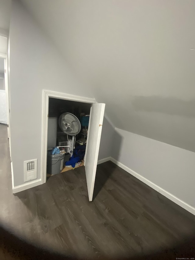 bonus room featuring dark wood-style floors, baseboards, visible vents, and vaulted ceiling