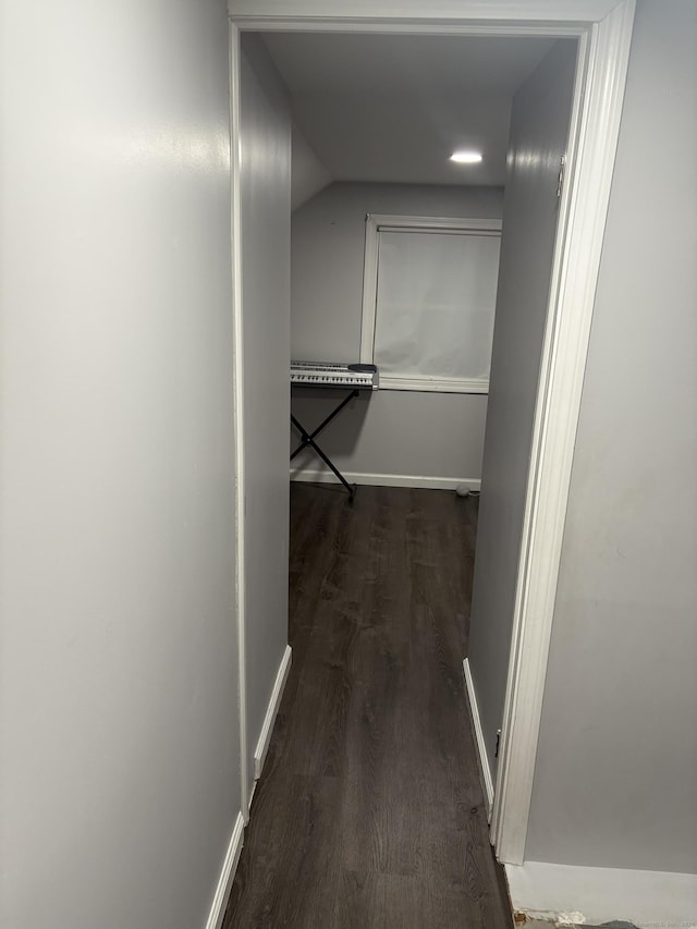 corridor with dark wood-style flooring and baseboards