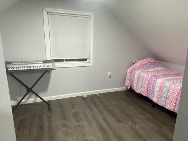 unfurnished bedroom featuring dark wood-style floors, vaulted ceiling, and baseboards