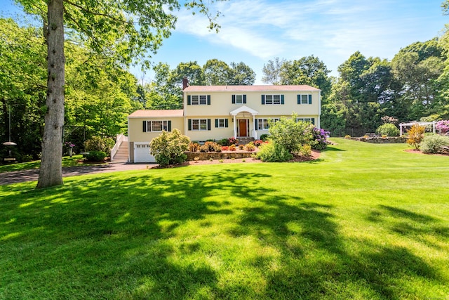 colonial home featuring a garage, a chimney, and a front lawn