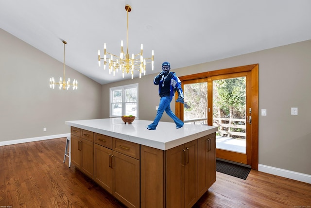 kitchen with baseboards, dark wood finished floors, lofted ceiling, light countertops, and a notable chandelier