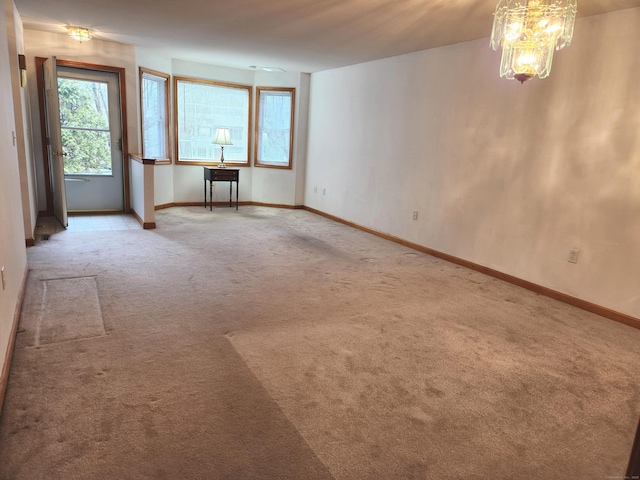 empty room with carpet, an inviting chandelier, and baseboards