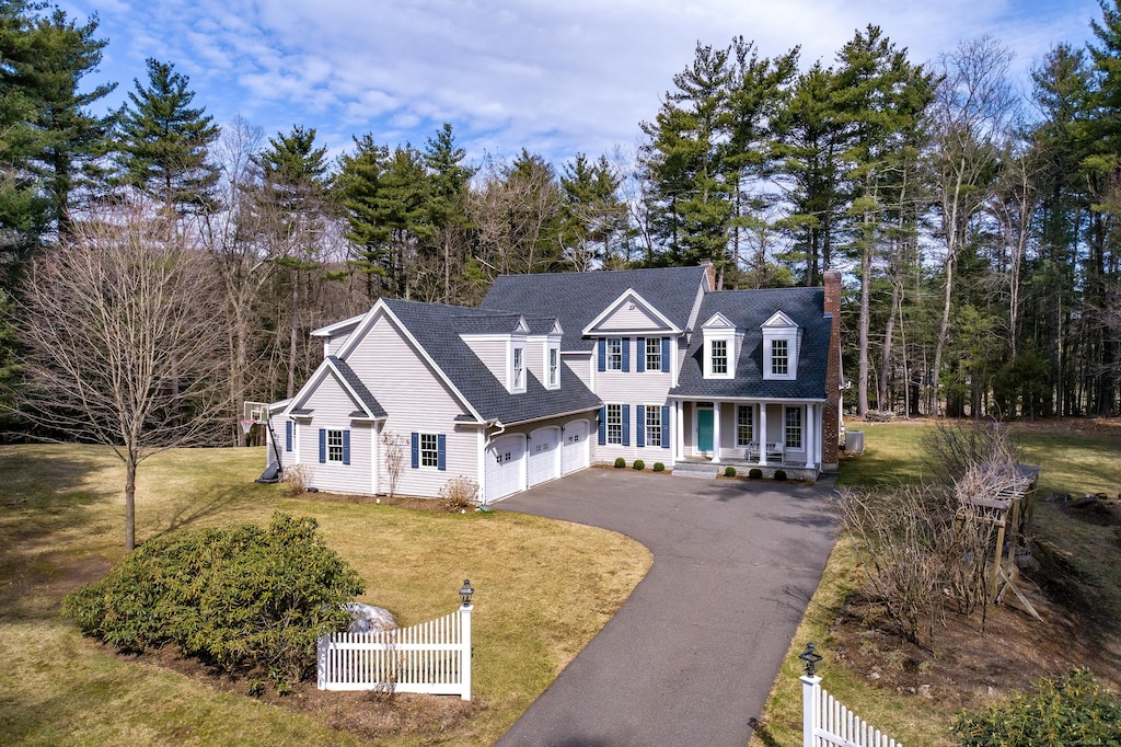 view of front of home with an attached garage, aphalt driveway, a fenced front yard, and a porch