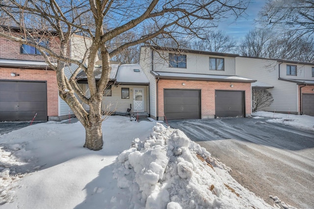 view of property with an attached garage, aphalt driveway, and brick siding