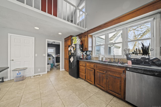 kitchen featuring freestanding refrigerator, light tile patterned flooring, a sink, dishwasher, and baseboards