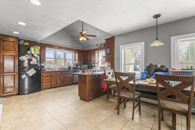 kitchen with dark countertops, stainless steel appliances, a wealth of natural light, and decorative light fixtures