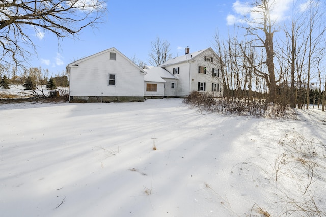 snow covered property with a chimney