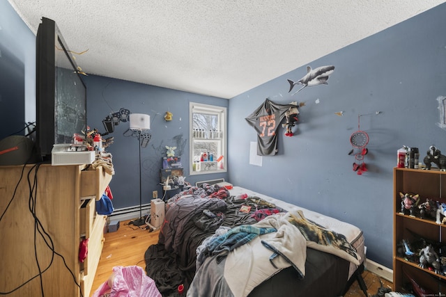 bedroom with a textured ceiling, baseboard heating, and wood finished floors