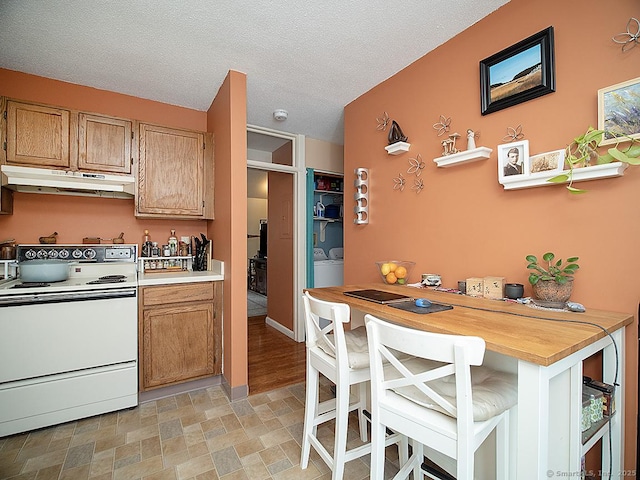 kitchen with a textured ceiling, under cabinet range hood, light countertops, washing machine and clothes dryer, and white electric range oven