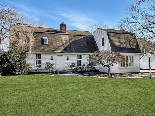 rear view of house featuring a shingled roof, a lawn, a chimney, and a gambrel roof