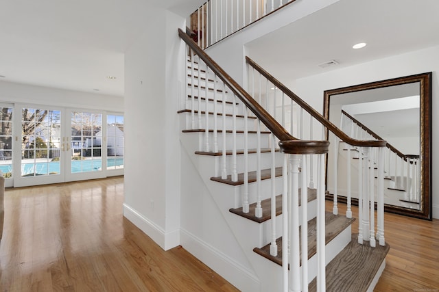 staircase featuring recessed lighting, wood finished floors, visible vents, baseboards, and french doors