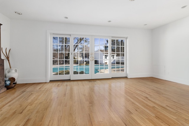 empty room with baseboards, plenty of natural light, and light wood finished floors