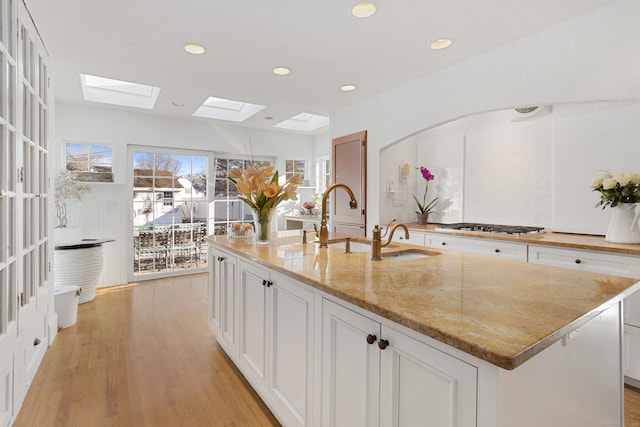 kitchen with light wood finished floors, white cabinets, light stone countertops, stainless steel gas stovetop, and recessed lighting