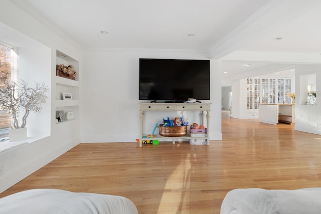 living area featuring baseboards, crown molding, light wood-style flooring, and built in features