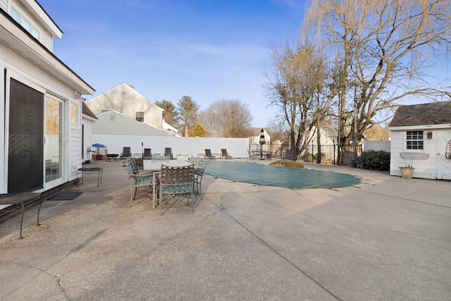 view of pool featuring a fenced in pool, an outbuilding, outdoor dining area, a patio area, and a fenced backyard