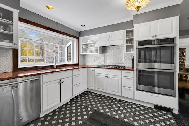 kitchen with stainless steel appliances, white cabinets, a sink, and ornamental molding