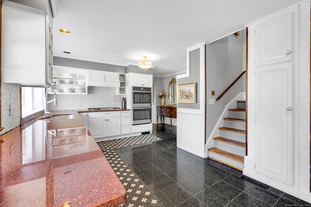 kitchen with a wainscoted wall, appliances with stainless steel finishes, granite finish floor, and white cabinets