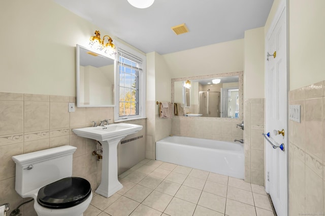 full bathroom with a garden tub, tile walls, toilet, and tile patterned floors