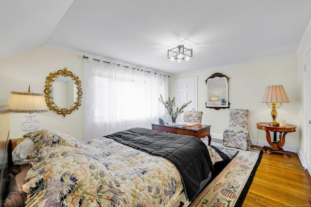 bedroom featuring lofted ceiling, baseboards, and wood finished floors