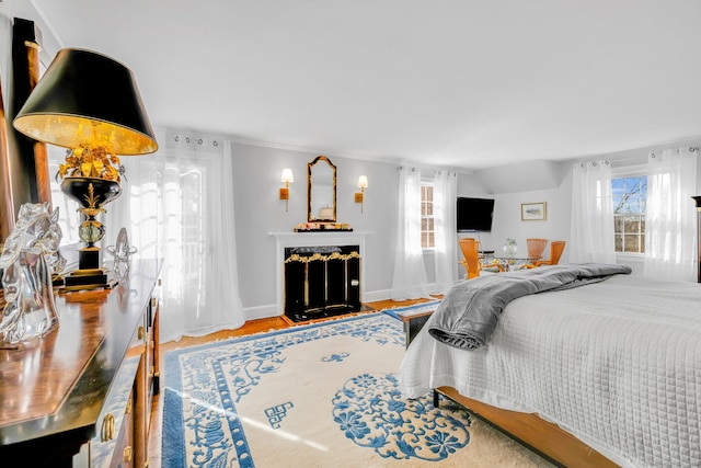 bedroom with a fireplace, baseboards, vaulted ceiling, and wood finished floors