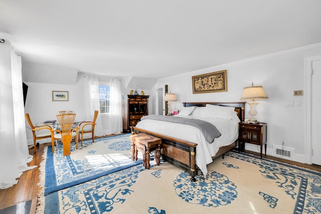 bedroom featuring visible vents, baseboards, and wood finished floors