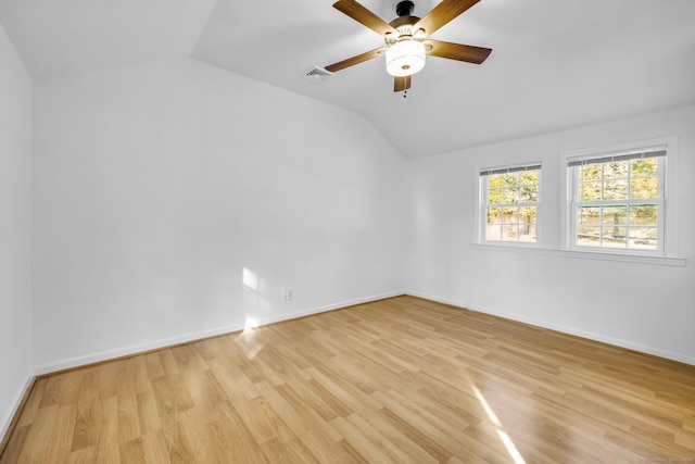 spare room featuring light wood finished floors, baseboards, visible vents, a ceiling fan, and lofted ceiling