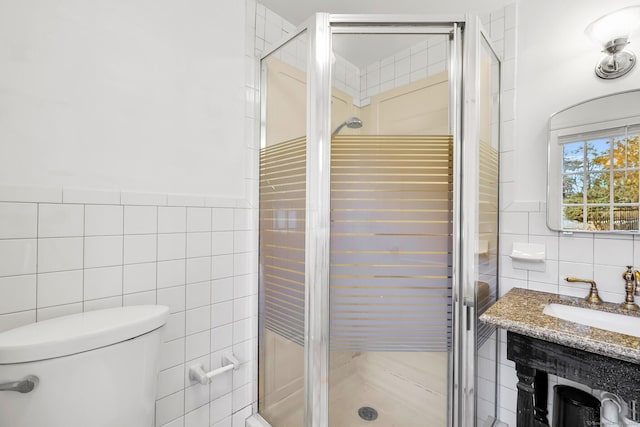 bathroom with toilet, a stall shower, vanity, and tile walls