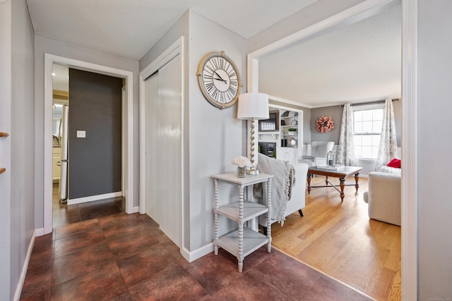 hallway featuring a textured ceiling, baseboards, and wood finished floors