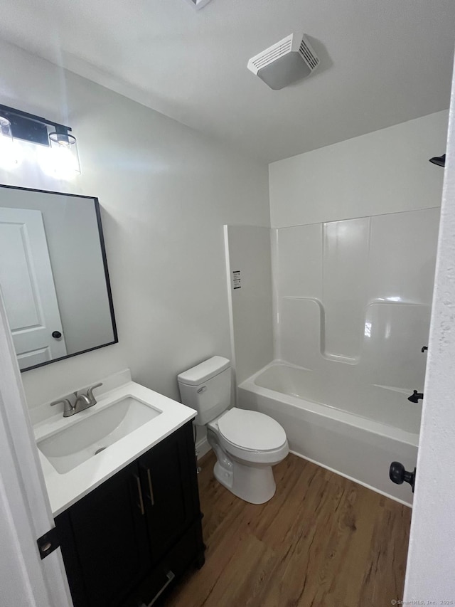 bathroom with toilet, shower / bathtub combination, vanity, and wood finished floors